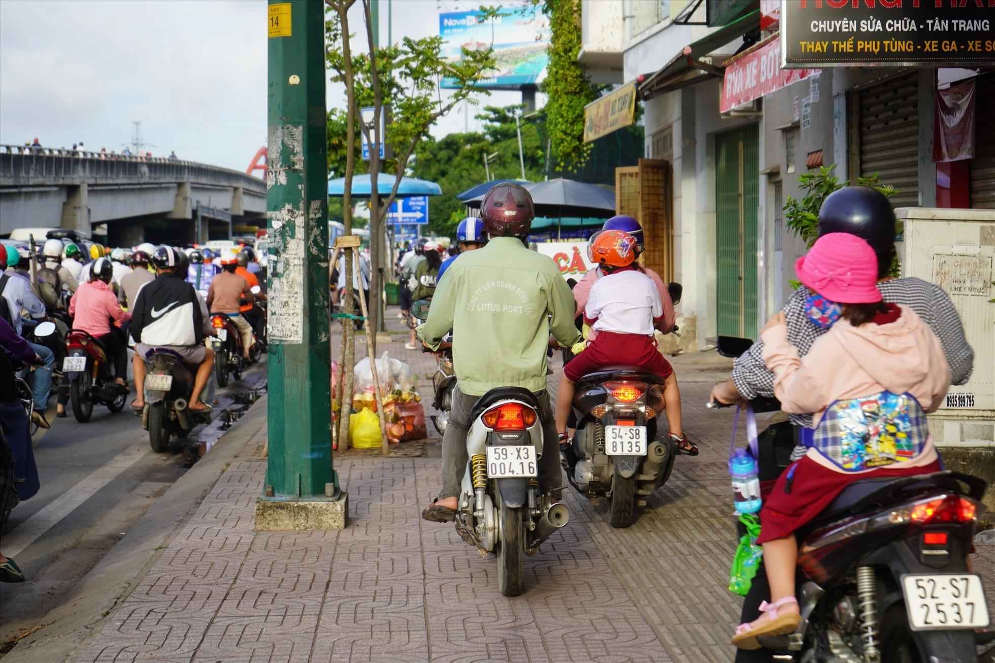 Nhiều phụ huynh chở con đi khai giảng phải chạy xe lên vỉa hè để kịp đến trường.