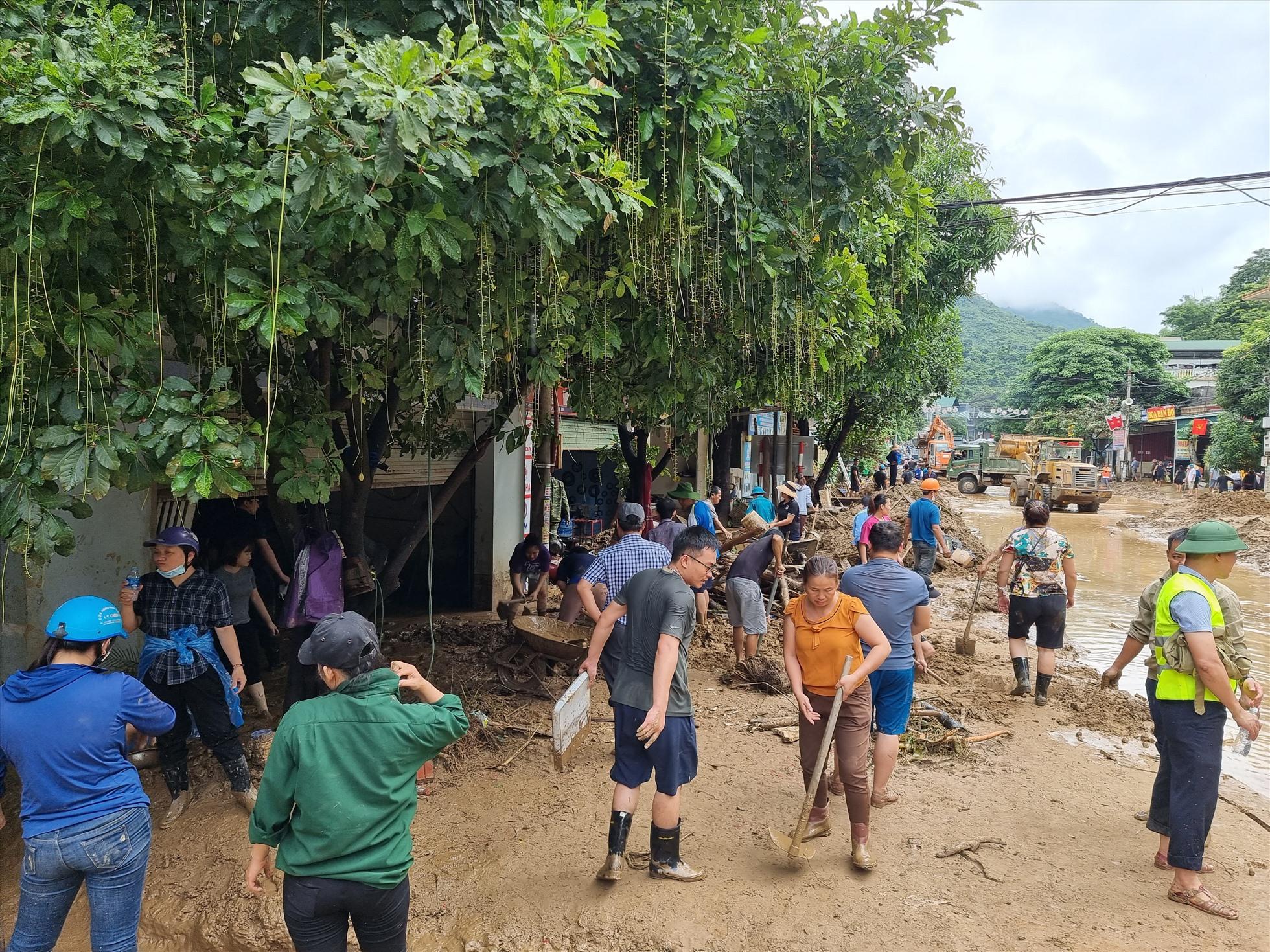 Người dân tất bật tham gia dọn bùn rác, giải phóng cửa ra vào của nhà mình.