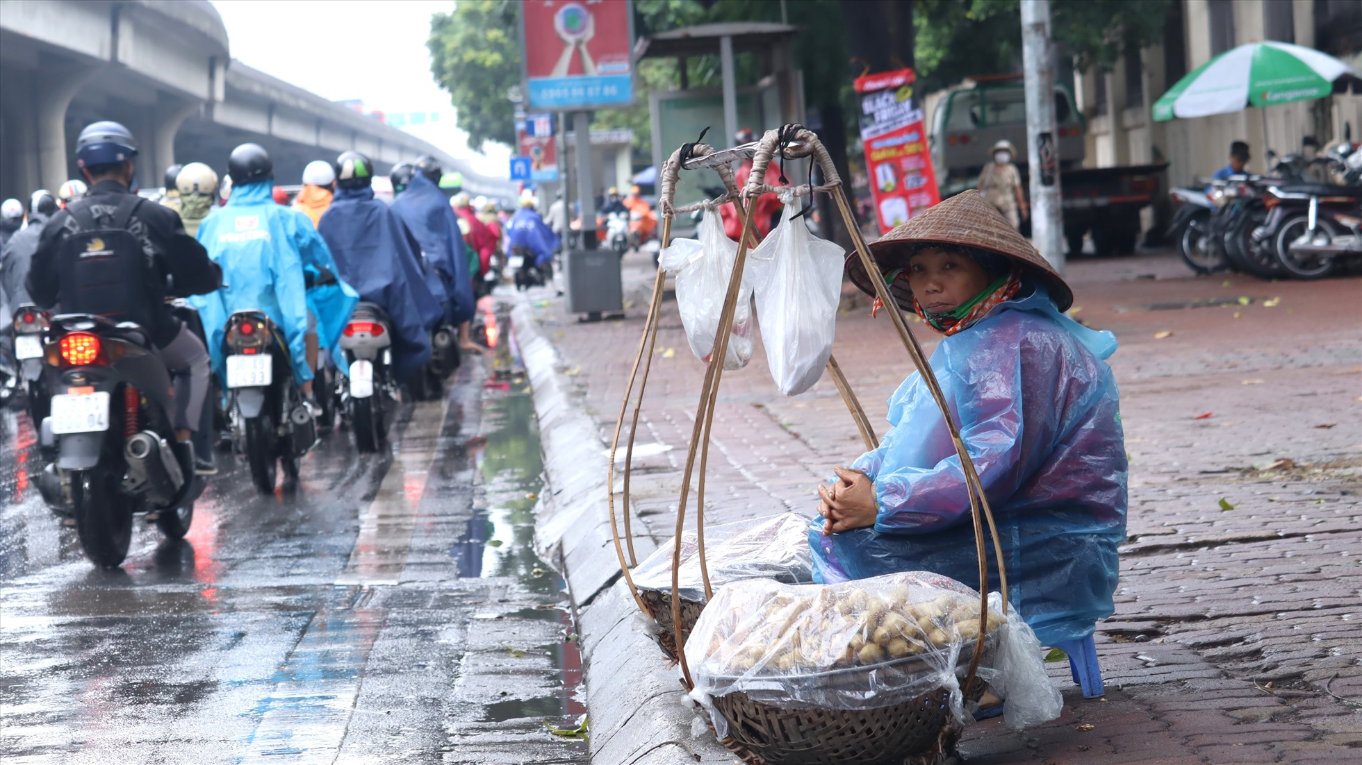 Người phụ nữ cùng gánh hàng rong mưu sinh giữa trời mưa lạnh.
