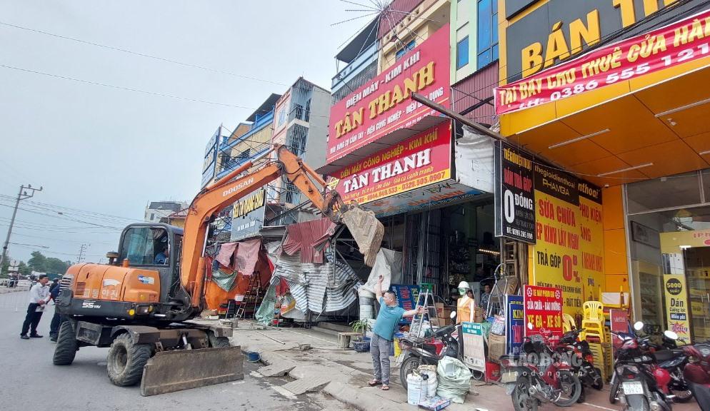 Lực lượng chức ăng tiến hành xử lý, tháo dỡ các biển bảng quảng cáo của các hộ kinh doanh lấn chiếm vỉa hè, hành lang an toàn giao thông tại đường gom cao tốc Hà Nội - Bắc Giang. Ảnh: Nguyễn Kế