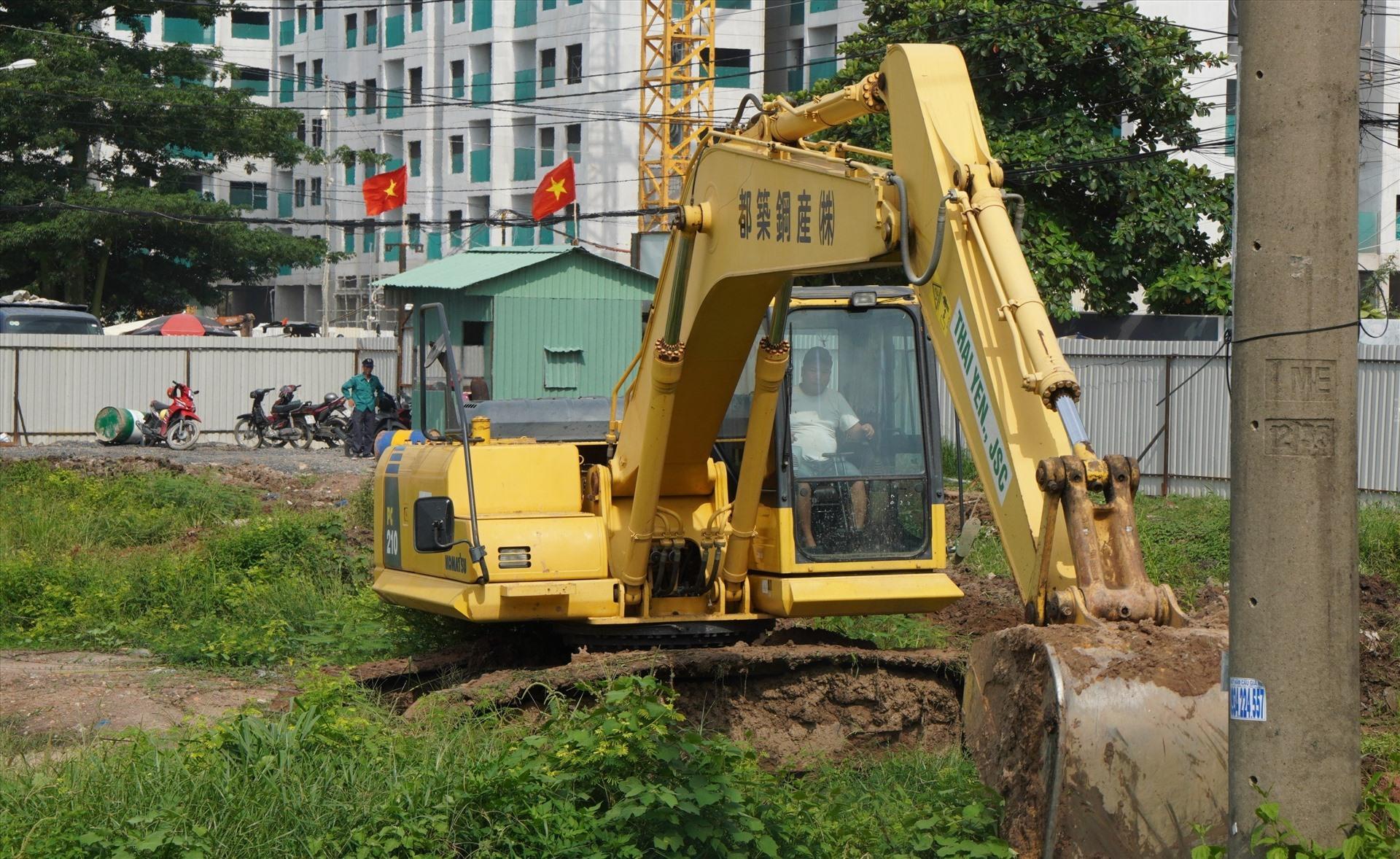 Trong công trường, máy móc, công nhân đang tiến hành công tác san ủi mặt bằng.