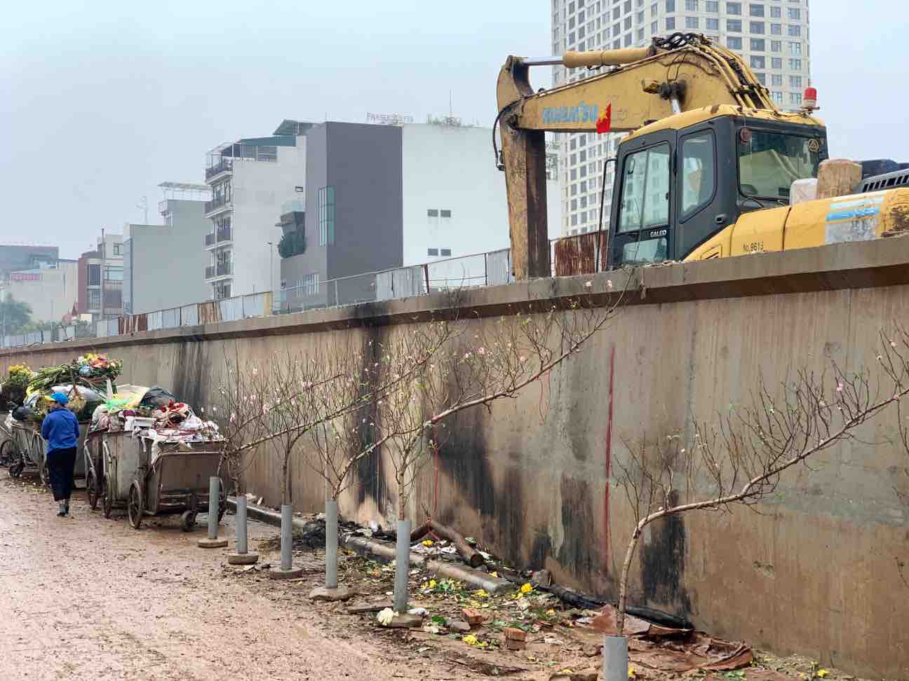 Tiểu thương phải trưng bày cành đào bên cạnh công trường nhếch nhác. Ảnh: Nhật Minh