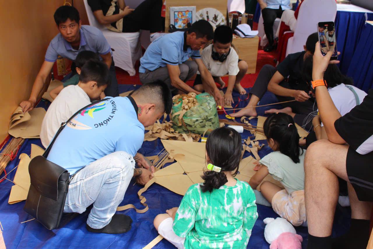 Các nghệ nhân, thợ giỏi của làng Bá Dương Nội hướng dẫn các em nhỏ tự tay làm ra những chiếc diều giấy xinh xắn, đẹp mắt.