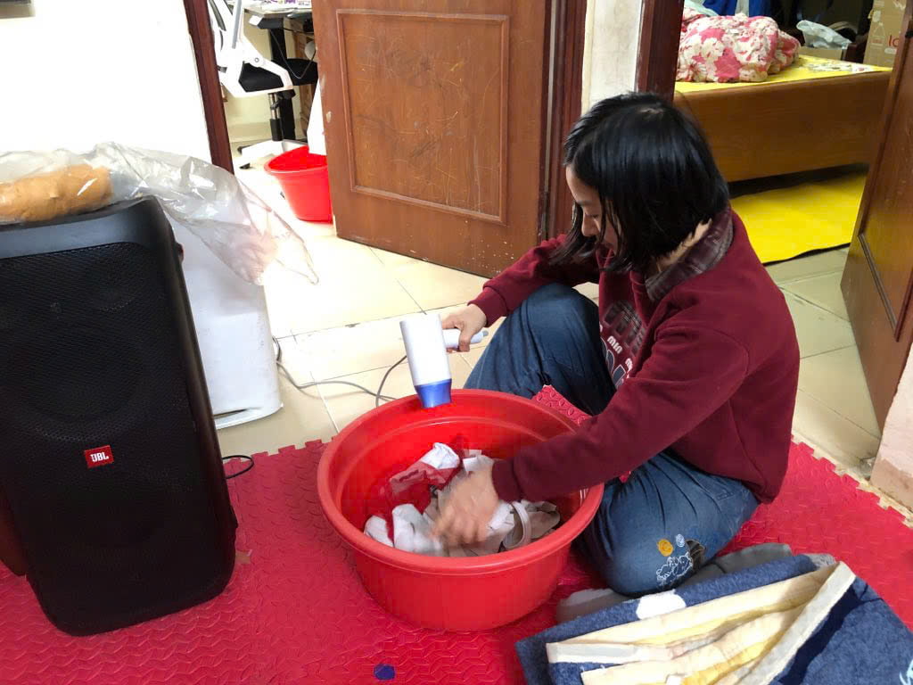 Chị Lê Thị Ngà dùng máy sấy tóc để sấy quần áo trong những ngày nồm ẩm. Ảnh: Phương Hân.