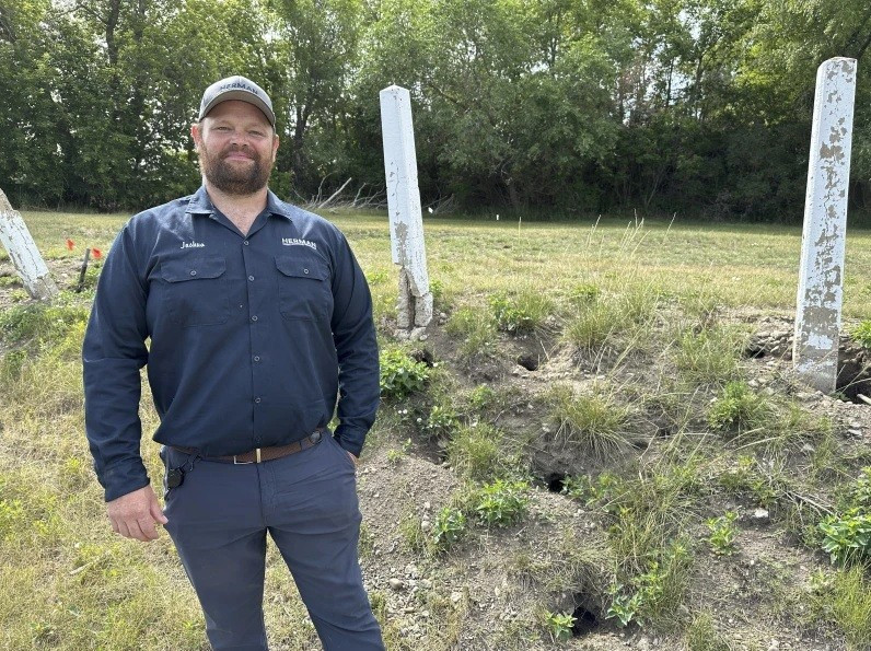 Ông Joshua Herman, chủ sở hữu/người điều hành Dịch vụ Kiểm soát Sâu bọ Herman, bên cạnh những cái hố do sóc đất Richardson đào ở Minot, Bắc Dakota (Ảnh AP/Jack Dura) hang-trieu-soc-dat-tung-hoanh-thanh-pho-my-phai-cau-cuu-chuyen-gia.jpg