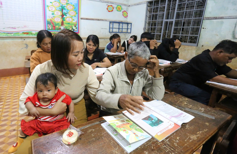 Giáo viên vừa bế con giúp học viên vừa dạy chữ.