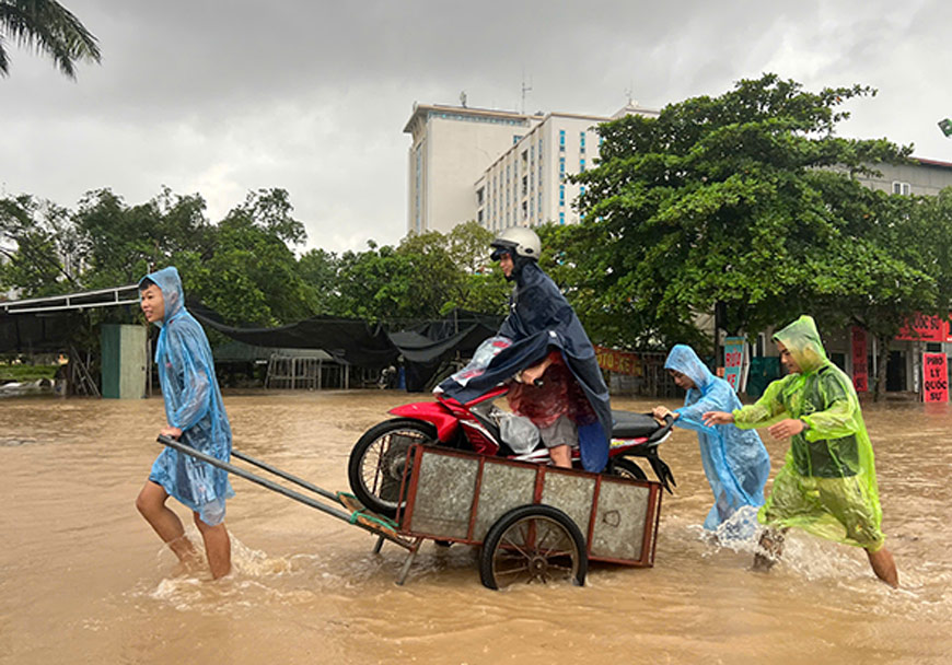 Người dân thuê dịch vụ xe kéo để đưa xe máy qua điểm ngập. Ảnh: Cường Ngô