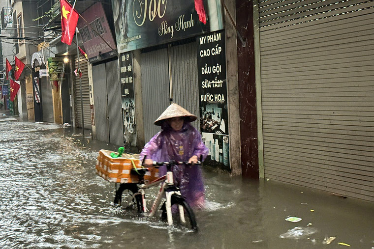 Người dân chật vật dắt xe qua điểm ngập. Ảnh: Tuấn Anh