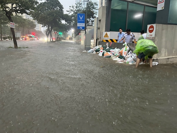 Nước ngập quá bánh xe ô tô tại phố Phạm Văn Bạch, các chung cư gia cố cửa hầm, tráng nước tràn vào. Ảnh: Thiều Trang