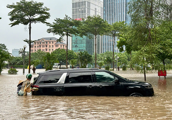 Người dân hỗ trợ tài xế đẩy xe khỏi vùng nước ngập. Ảnh: Tuấn Anh