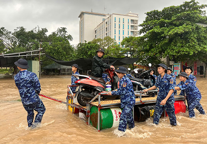 Lực lượng Quân đội giúp người dân chở xe máy qua khu vực ngập nước trên đường 70. Ảnh: Cường Ngô