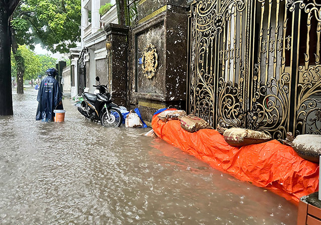 Người dân gia cố cửa nhà, tránh nước ngập sâu vào bên trong. Ảnh: Đinh Thiện - Thiều Trang