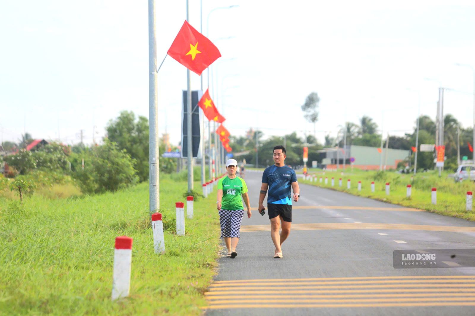 Người dân tập thể dục đi trên đường hàng cờ Tổ quốc rực rỡ.