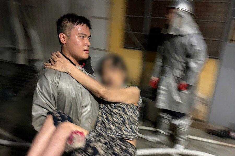 Hạ sĩ Hoàng Hải Long đưa nạn nhân trong vụ cháy trên phố Đội Nhân ra ngoài an toàn. Ảnh: Công an cung cấp